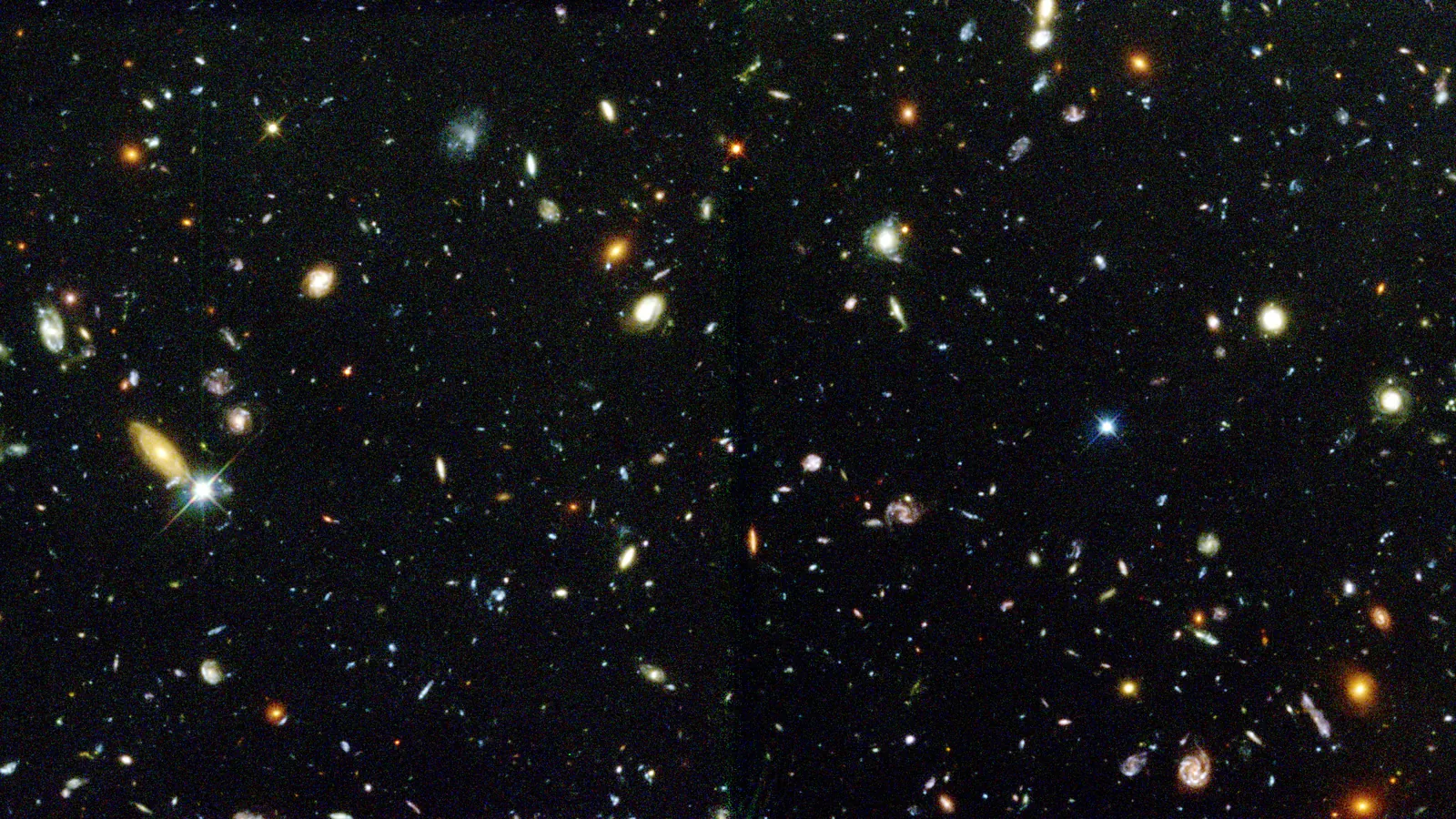 Part of the Hubble Deep Field, a black background crowded with spiral, elliptical and irregular galaxies