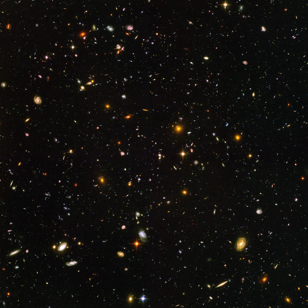 The Hubble Ultra Deep Field, a square image packed with about ten thousand galaxies, many of them faint red dots