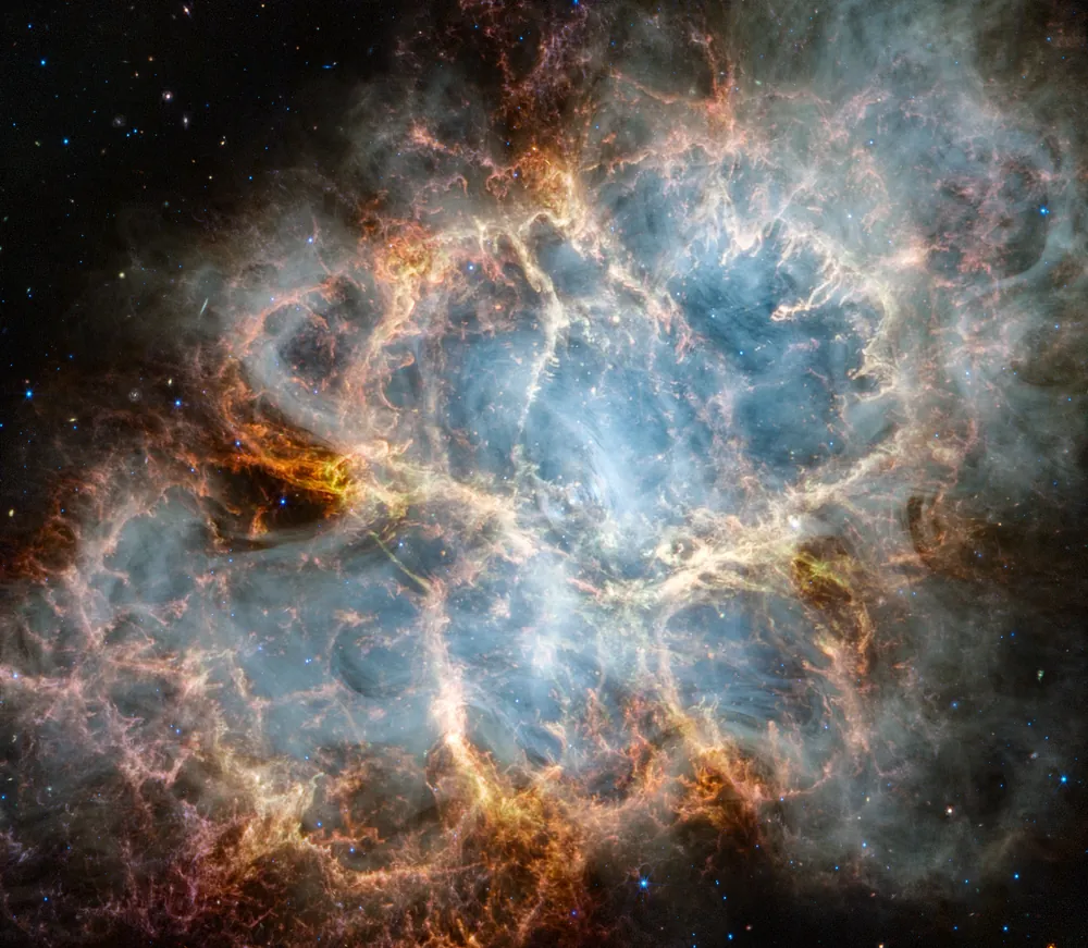 Webb image of the Crab Nebula, red-orange filaments of gas forming a cage around a milky, smoke-like interior